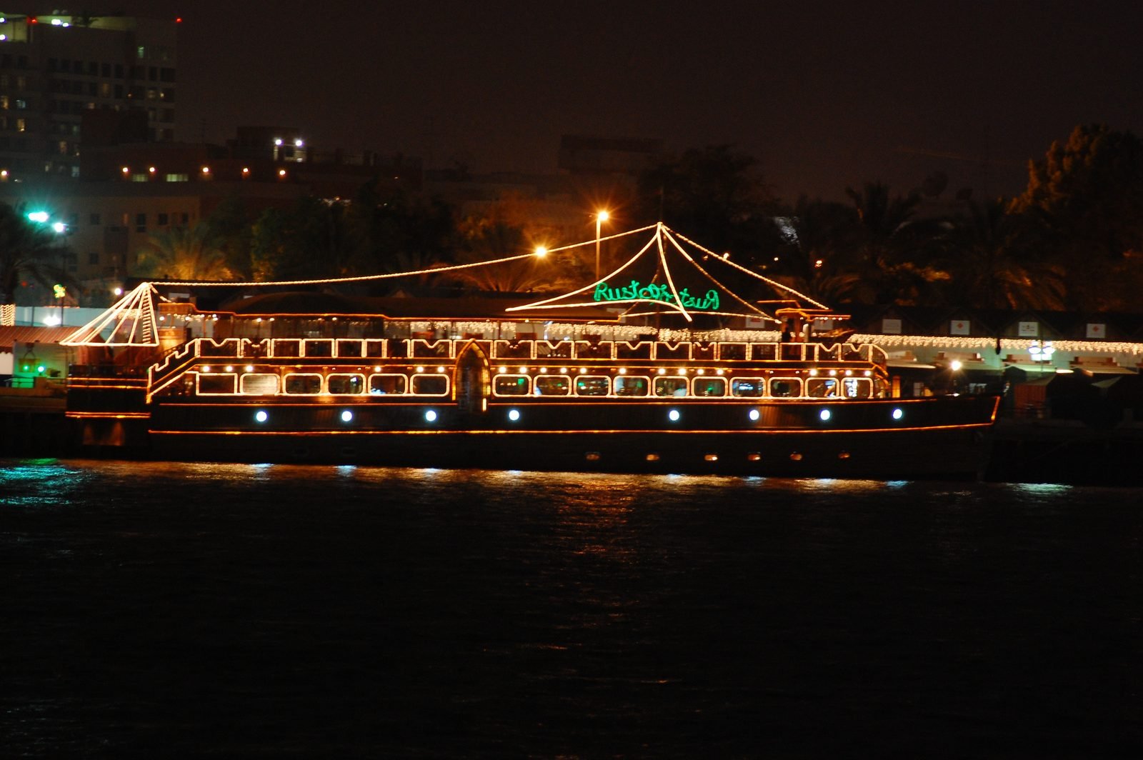A traditional wooden dhow lit up for an evening dinner cruise in Dubai Marina