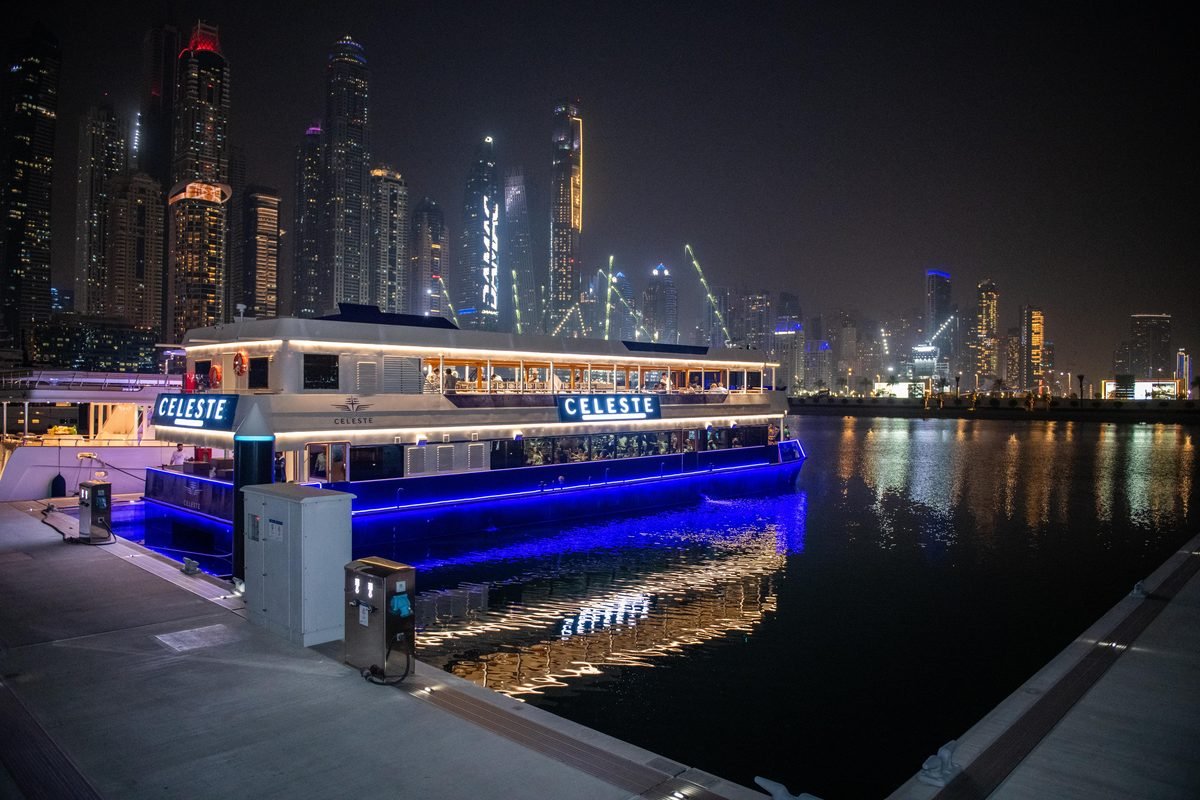 A modern glass dinner boat lit up at Dubai Marina at night, the premium end of the marina dhow cruise choices